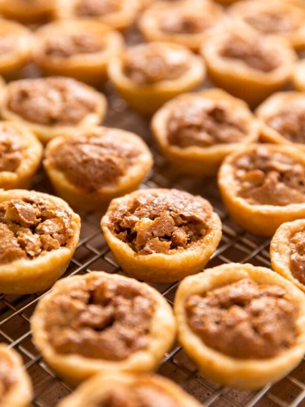 Small bite-size pecan tassies sitting on cooling rack in full sunlight