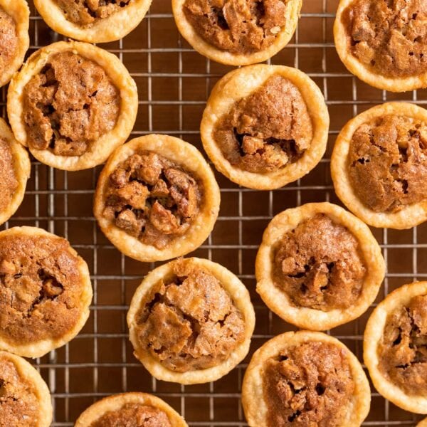 Top down view of multiple bite-size pecan tassies sitting on cooling rack