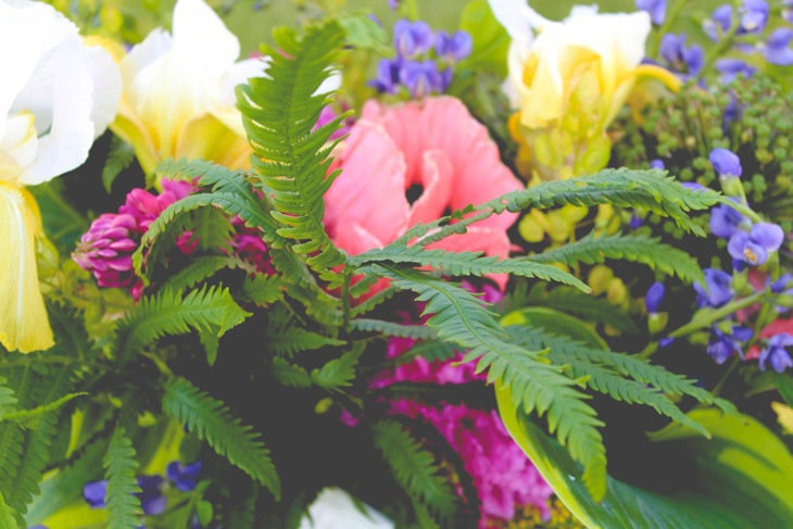 Bright summer flowers in a rustic arrangement with greens around the base.