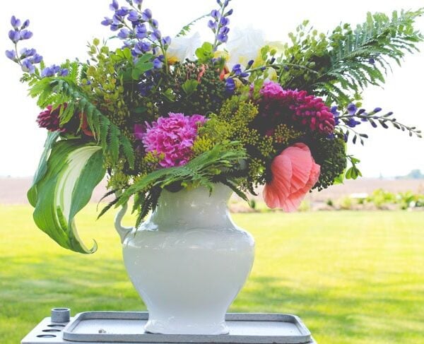 Finished rustic arrangement with lots of different flowers from the garden in an ironstone container during the summer season.
