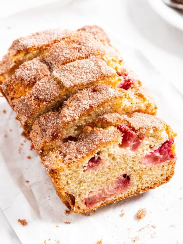 White piece of parchment with slices of rhubarb buttermilk cake stacked against each other with cinnamon sugar topping.