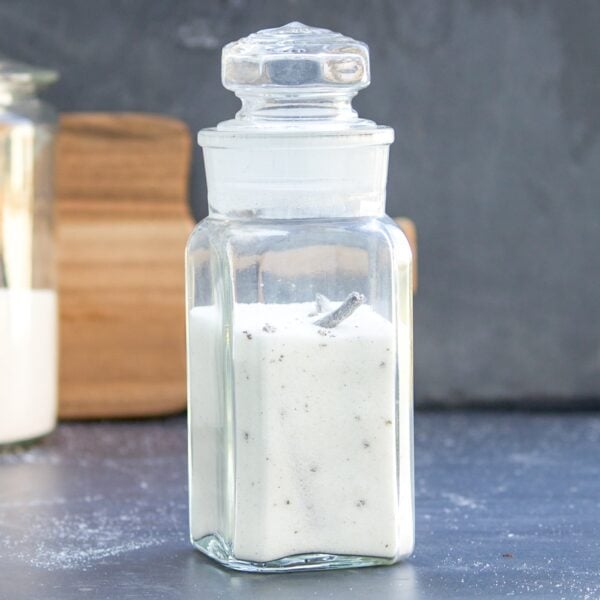 A jar full of vanilla sugar sits on a table.