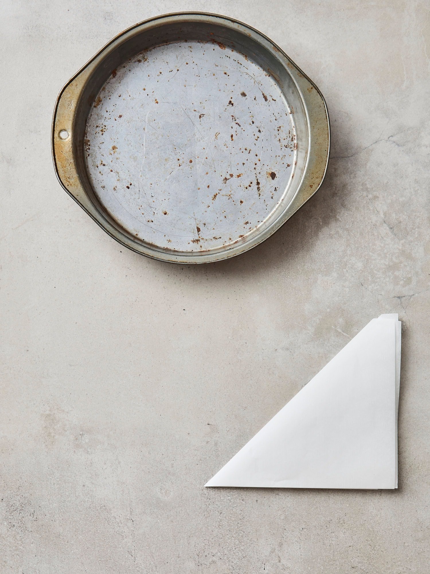 Cake pan with triangle of parchment folded.