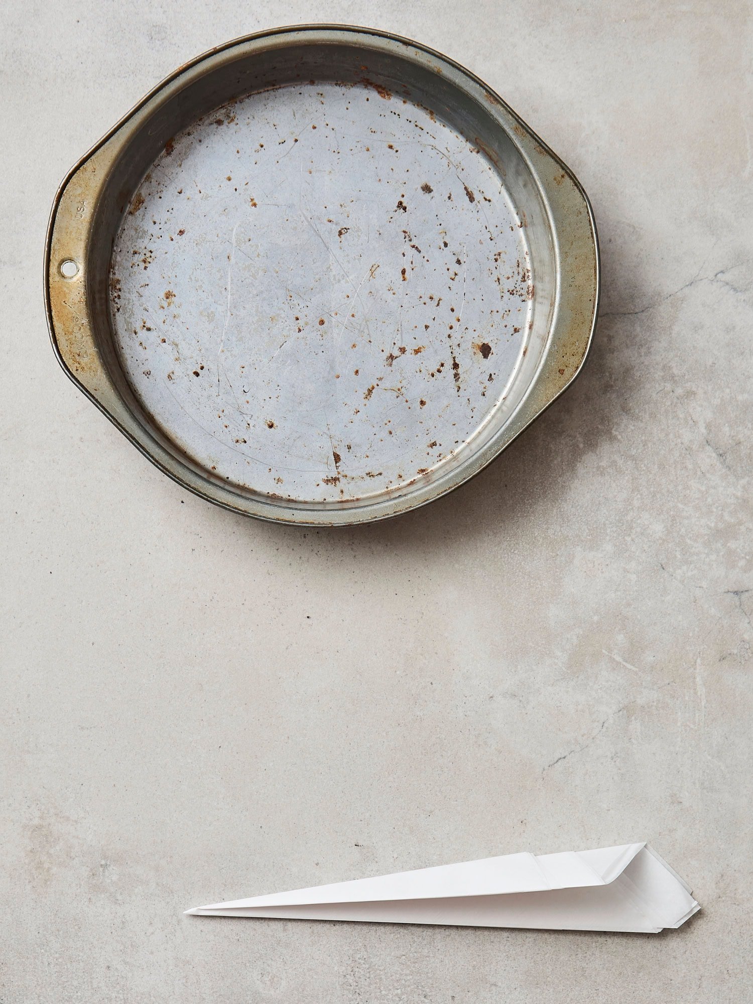 Cake pan with folded piece of parchment for a cake round.