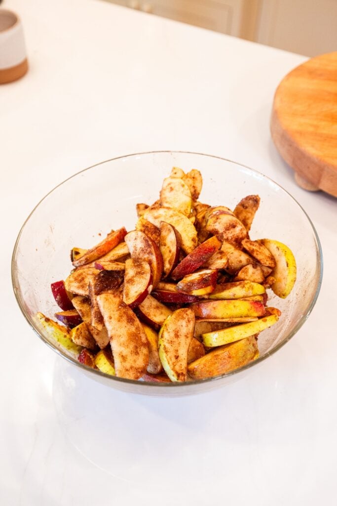 Glass bowl with mixture of sliced apples with cinnamon.