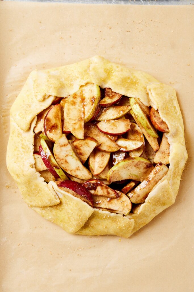 Pie of parchment paper with unbaked apple galette.