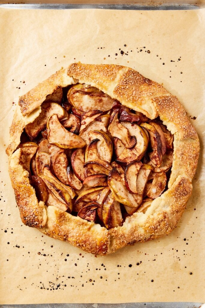 Fully baked apple galette sitting on a piece of parchment paper.