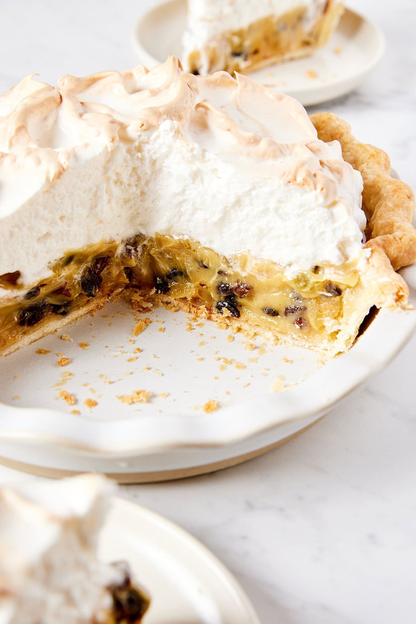 White pie plate with raisin pie with slices removed showing interior texture with dark raisins.
