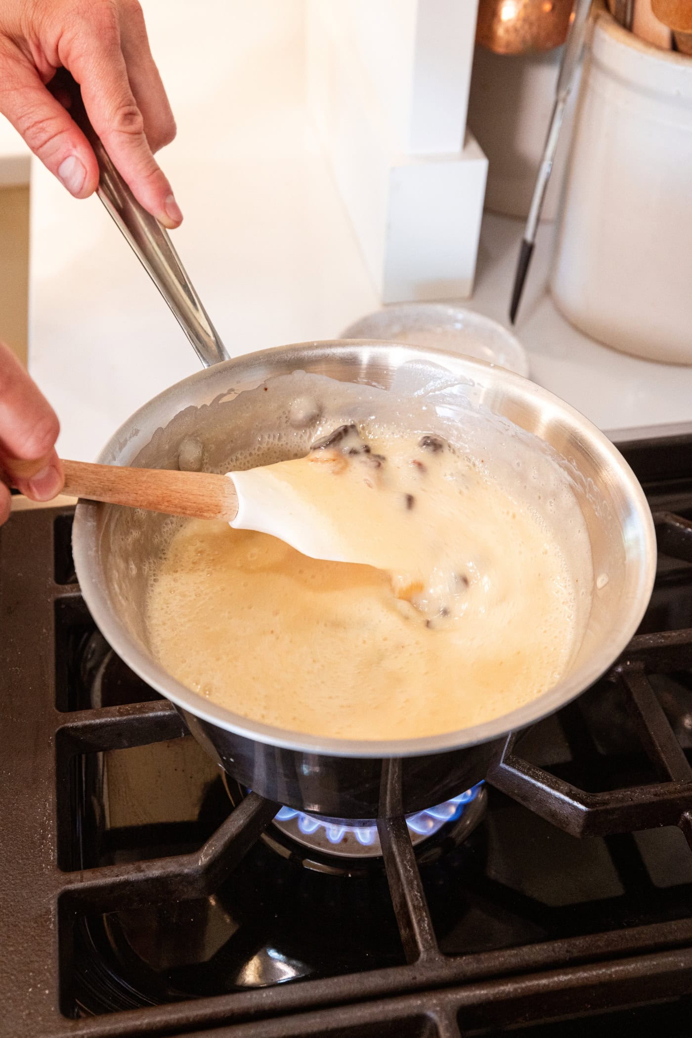Spatula mixing together thin-looking custard filling for raisin pie.