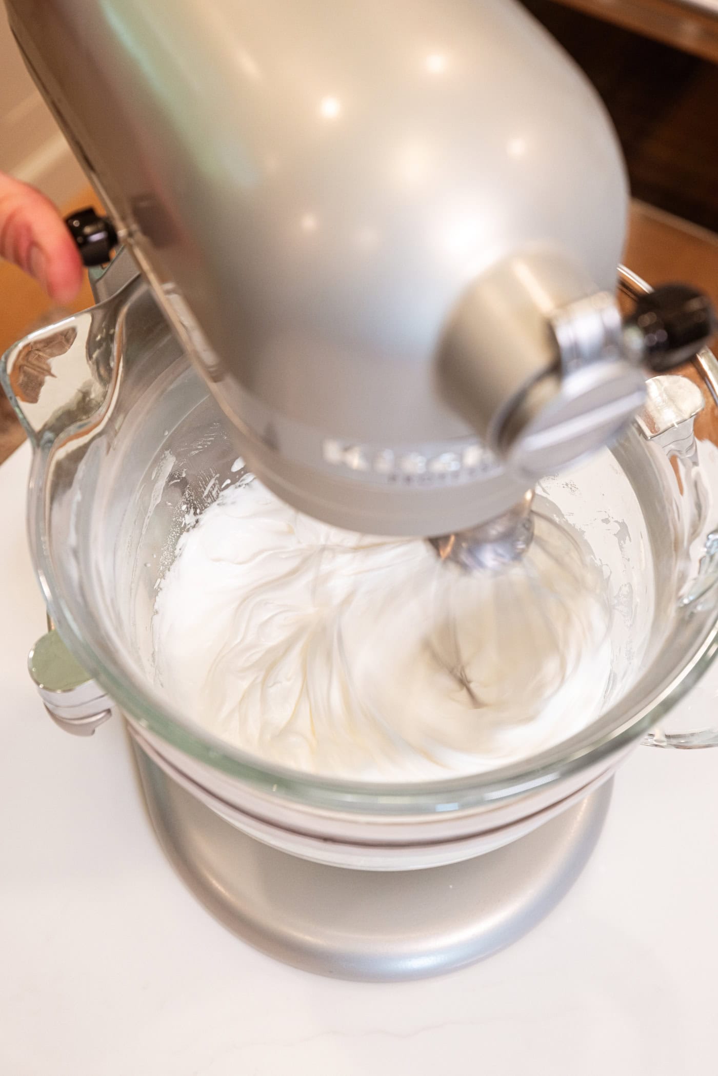 Large stand mixer mixing together whipped meringue topping after adding cream of tartar.