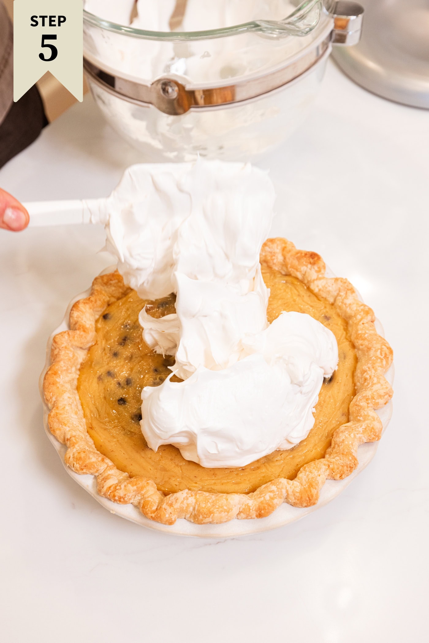 Dolloped of whipper meringue topping being piled on a raisin pie.