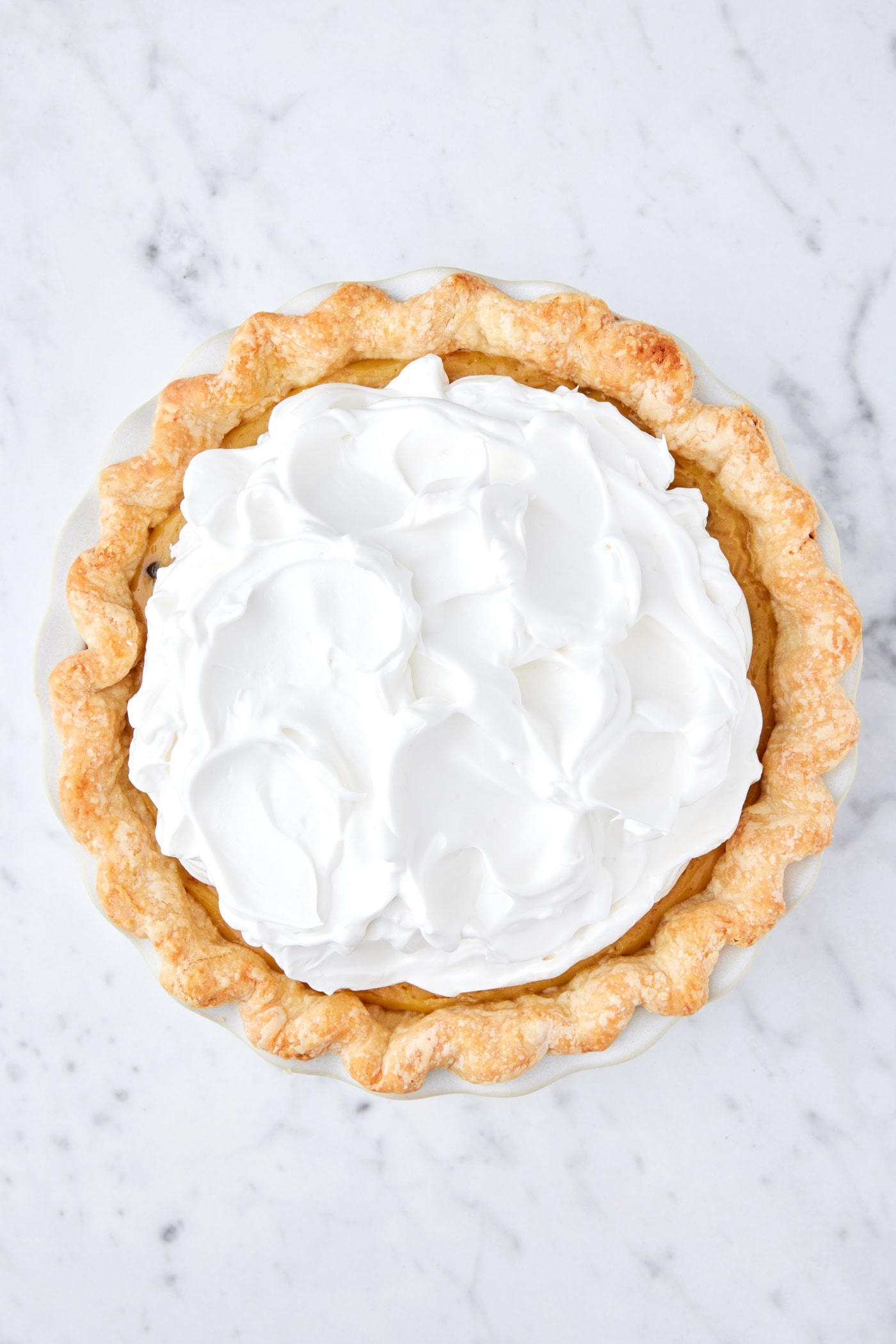 White marble surface with sour cream raisin pie with meringue topping before being browned in the oven.