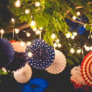 Lights strung from tree branches along with patriotic fourth of July pinwheels in red, white, and blue colors.