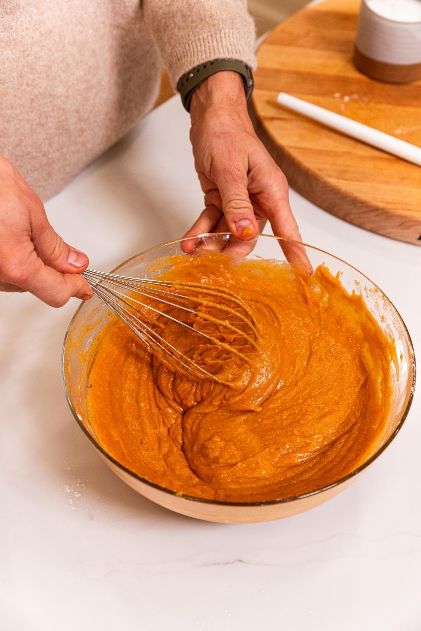 Large glass bowl filled with mixed pumpkin bar batter with whisk finishing mixing everything together.