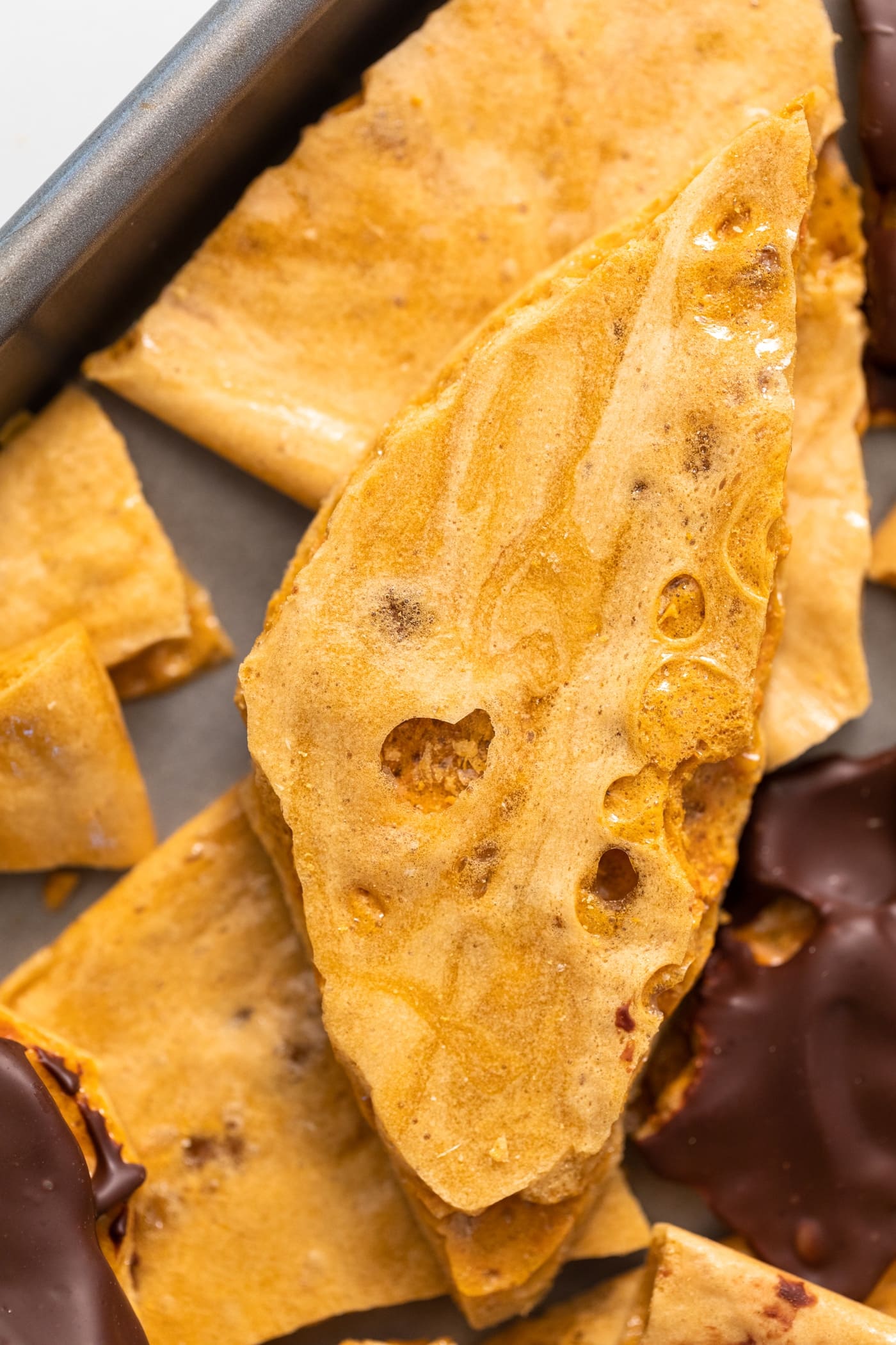 Top down view of large piece of yellow-colored candy sitting on top of other pieces of candy all on baking pan