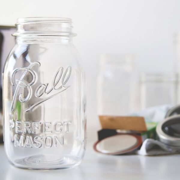 White countertop with canning supplies including glass jars, lids, rings, and a metal canner.