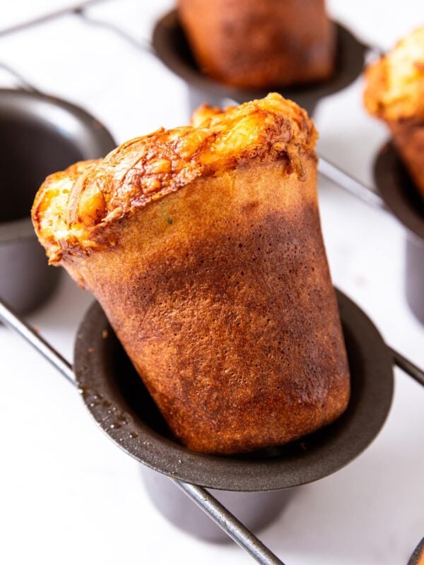 Baked and golden popover sitting in popover pan after coming out of oven.