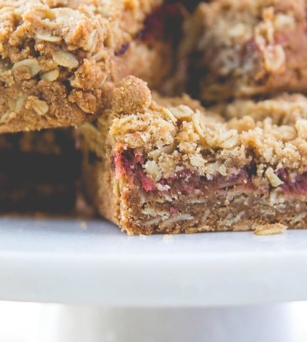 Stacks of rhubarb crumb bars sitting on white plate showing the middle jam layer of the bars