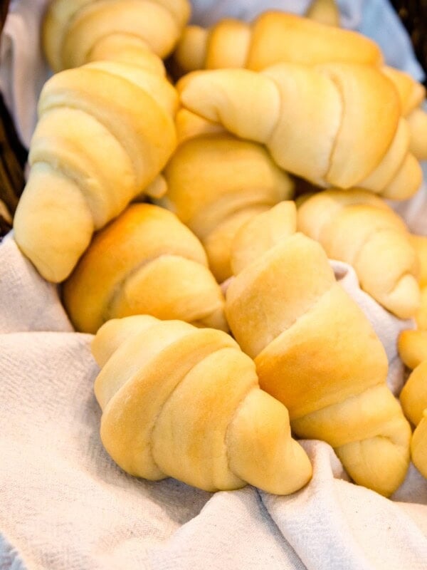 Golden brown butterhorns sitting in wood basket and white towel