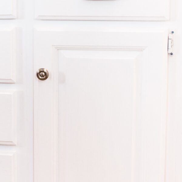 Matte silver drawer pulls attached to bright white lower kitchen cabinets