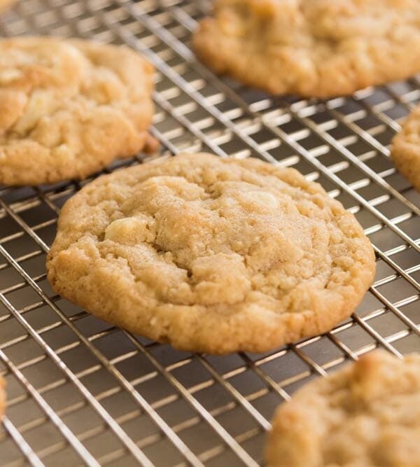 White chocolate chips showing in golden brown Macadamia nut cookies sitting on wire cooling rack with multiple cookies all around