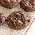 Spicy dark chocolate cookies sitting on wire cooling rack with extra pepitas sitting on white surface