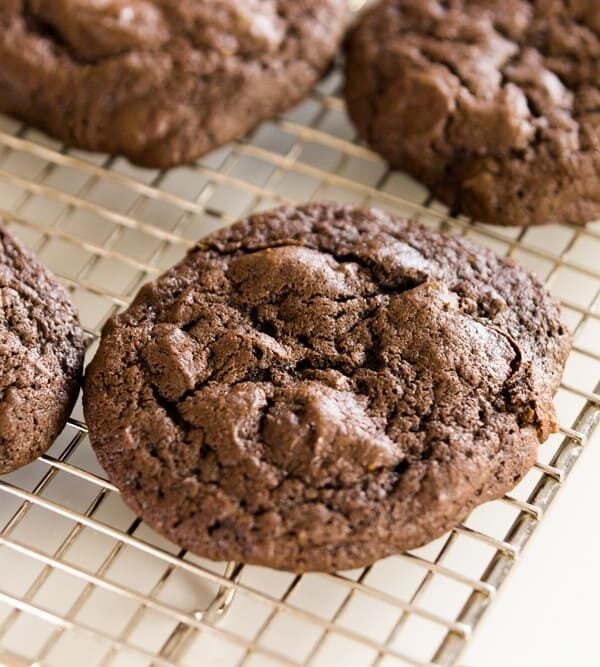 Spicy dark chocolate cookies sitting on wire cooling rack with extra pepitas sitting on white surface