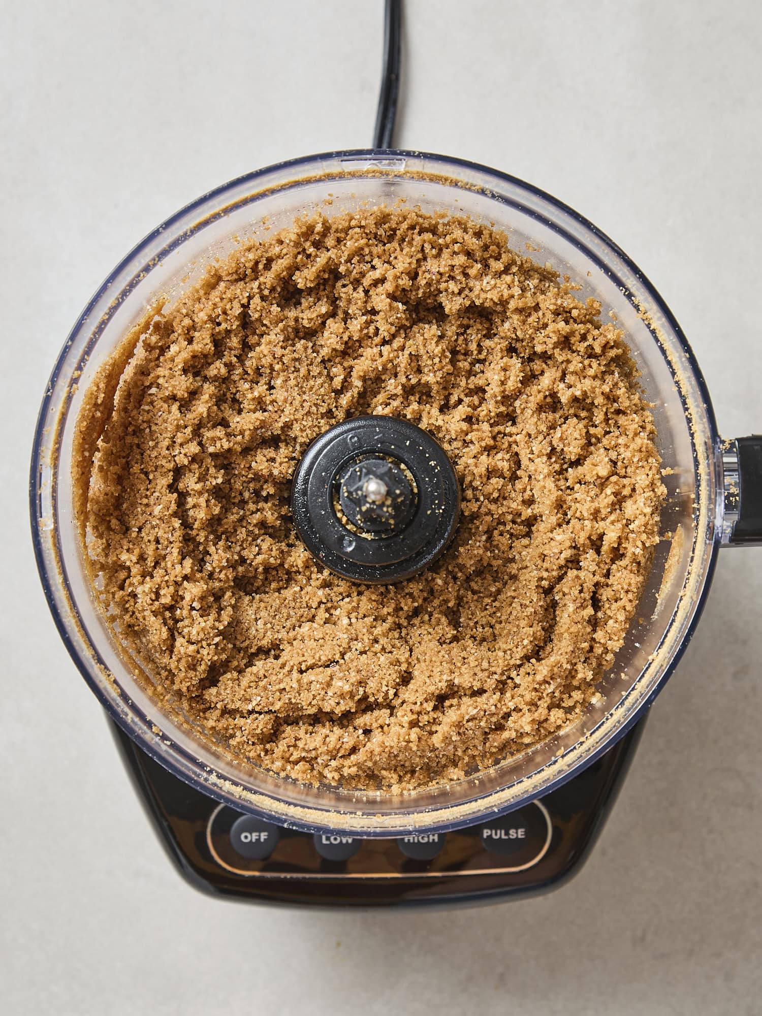 Food processor filled with crust for a pumpkin cheesecake.