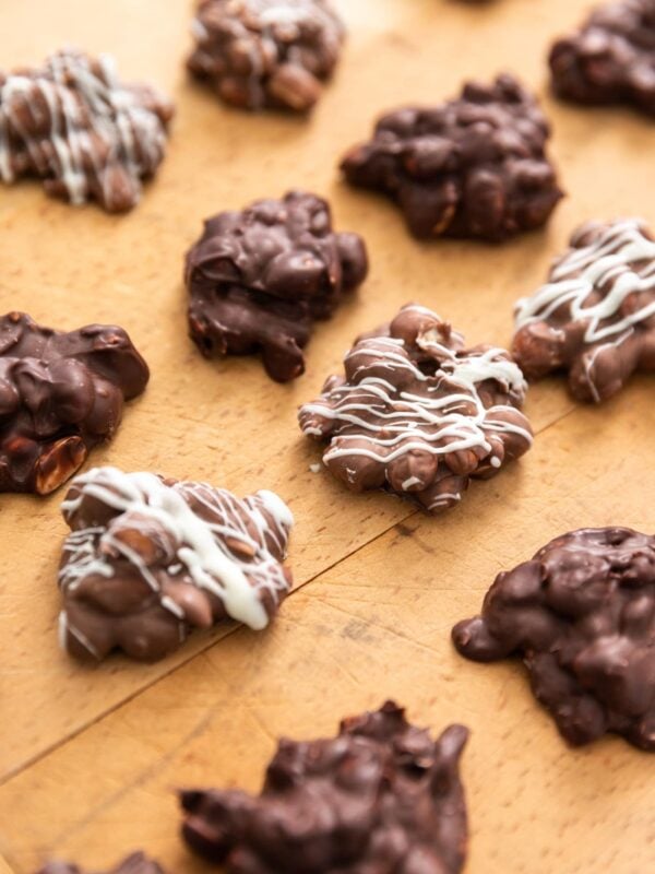 Chocolate peanut clusters sitting on wood board some drizzled with white chocolate