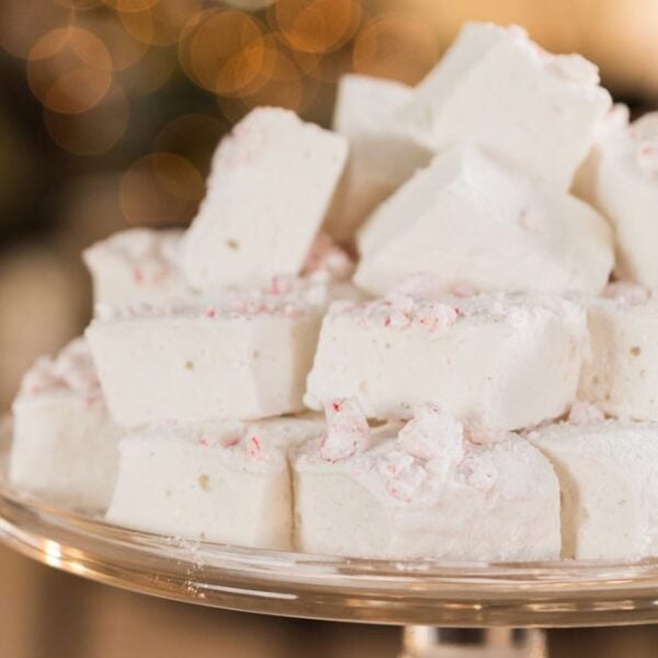 Glass platter filled with a stack of white and red colored peppermint marshmallows for the holiday season.