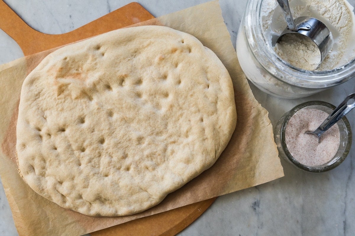 Baked pizza dough sitting on a cutting board with parchment.