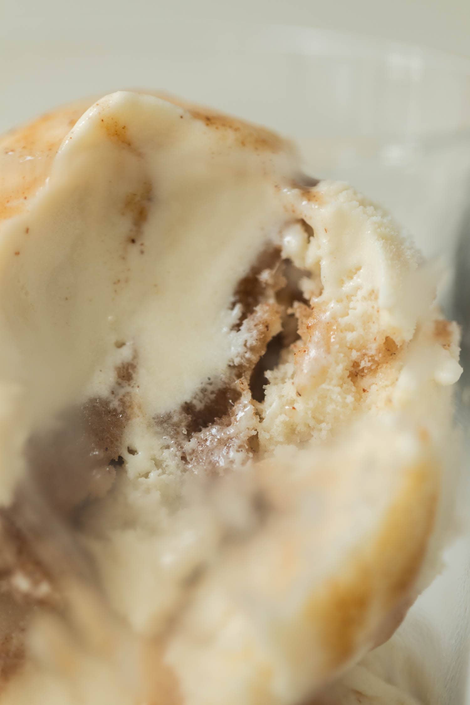 French toast ice cream drizzled with extra cinnamon sauce with a bite taken in a clear glass