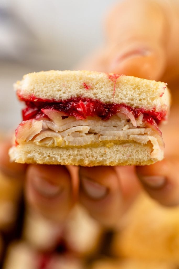Turkey cranberry croque monsieur held up to viewer with layers of turkey and cranberry jam with extra pieces of sandwich in background