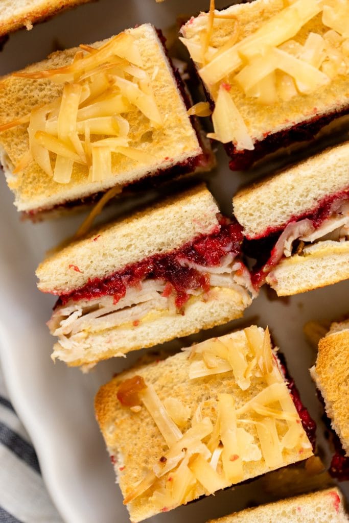 Turkey cranberry croque monsieur sitting on white plate with linen napkin underneath all on white surface