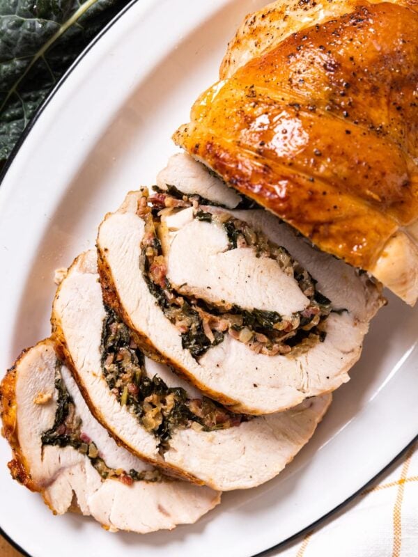 Top down view of white plate with slices of turkey roulade laying on the side with stuffing in middle of each roll