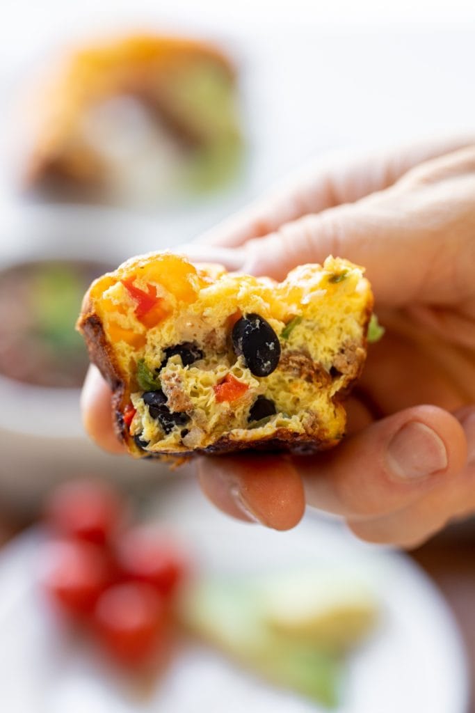 Cross-section view of huevos rancheros egg cups being held by hand with extra egg cups in background
