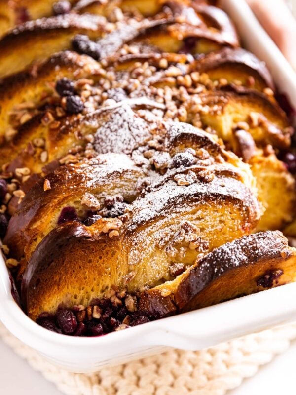 White baking dish filled with golden brown blueberry French toast topped with a light dusting of powdered sugar