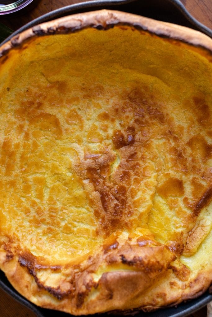 Top down view of citrus Dutch baby in a red skillet on wood surface