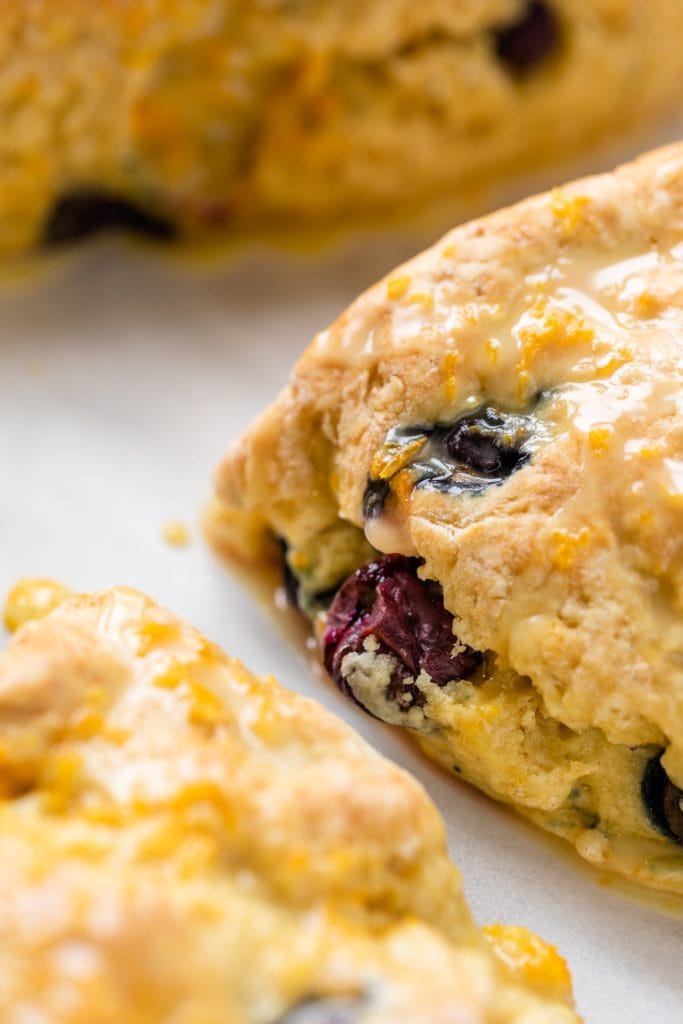 Close up view of side of Irish soda bread scone sitting on piece of parchment with extra scones around