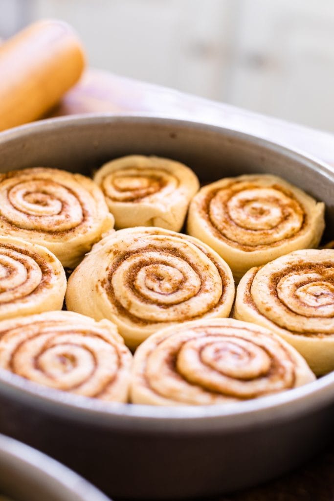 Unbaked cinnamon rolls sitting in metal pan ready to rise and swirled with cinnamon and sugar mixture