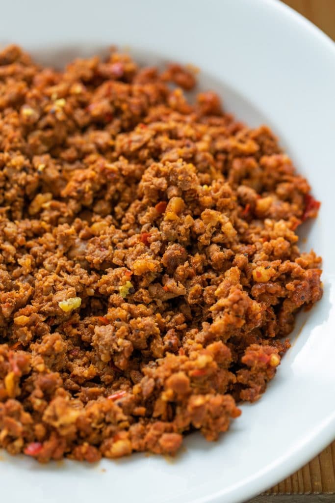 Cooked chorizo sausage sitting in white bowl on wood surface