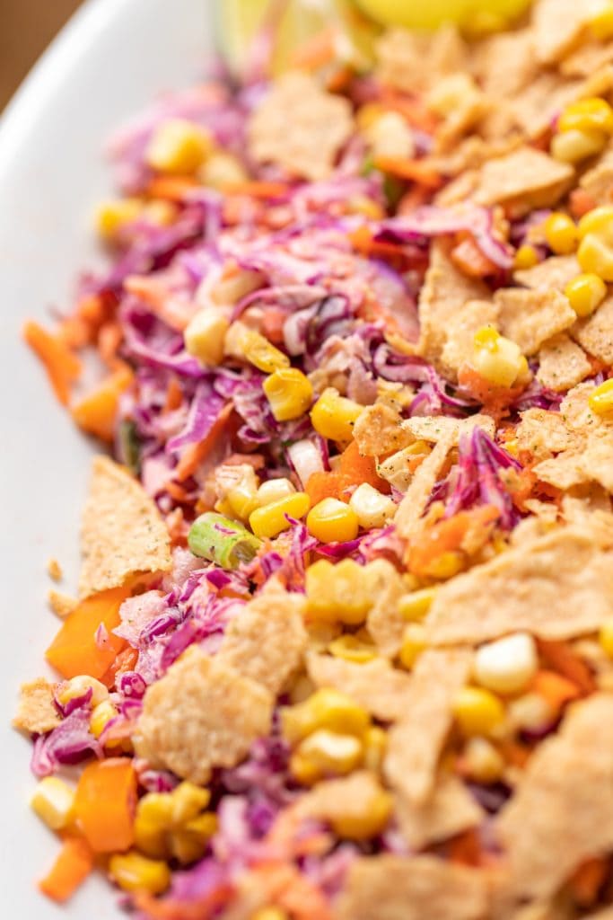 Coleslaw created from red cabbage served with corn and tortilla chips on white serving platter