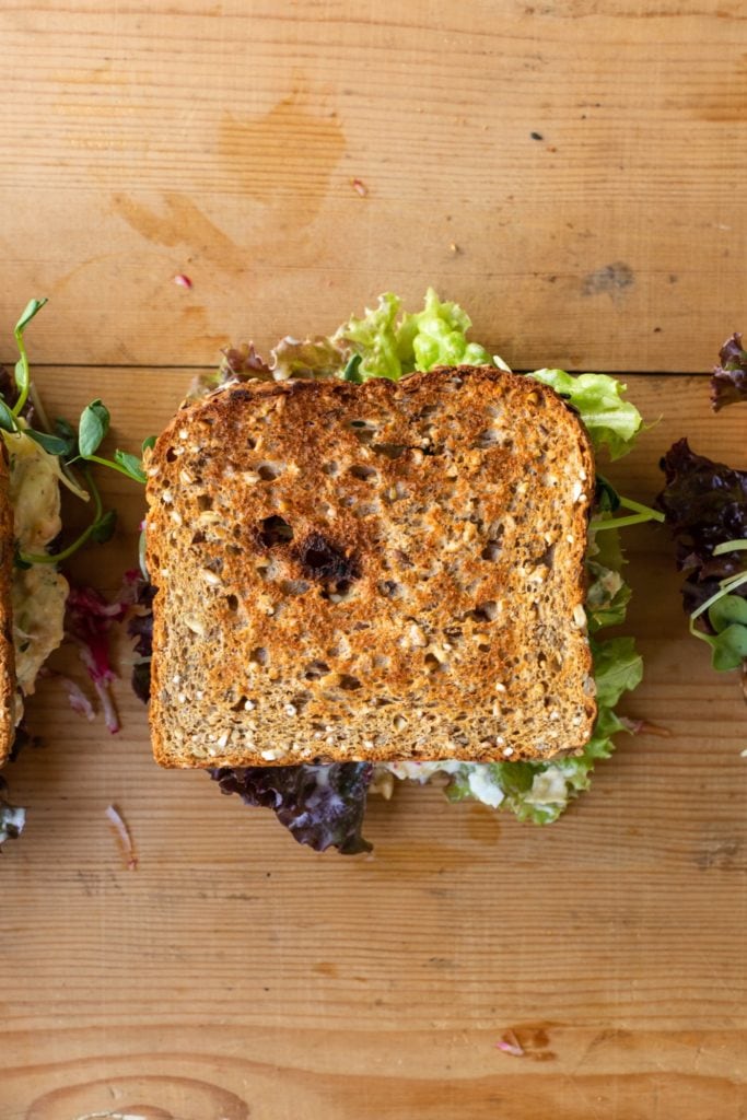 Top down view of sandwich with lettuce and chickpea sitting on wood board