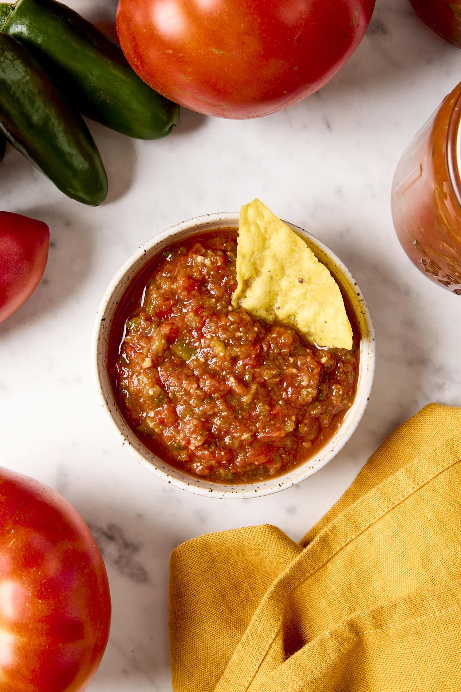 Small bowl filled with salsa with a tortilla chip sitting in salsa.