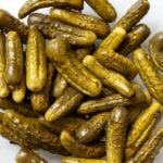 Pile of pickles sitting in a glass bowl after fermenting.