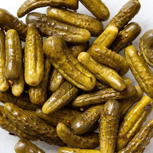Pile of pickles sitting in a glass bowl after fermenting.
