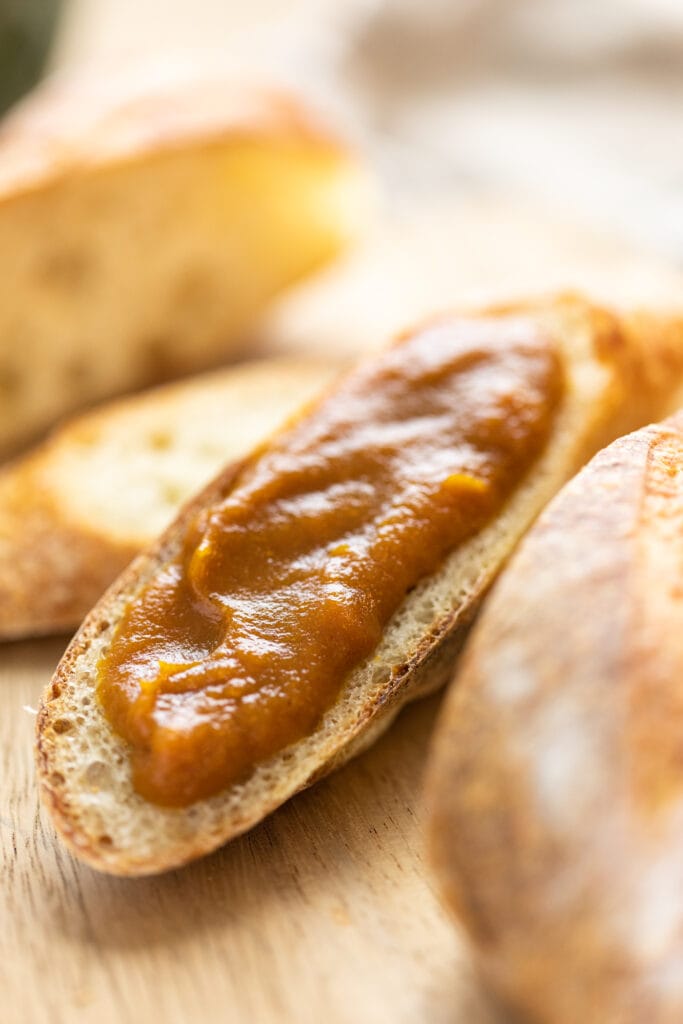 Close up view of brown colored pumpkin apple butter spread on top of piece of French toast sitting on wood cutting board