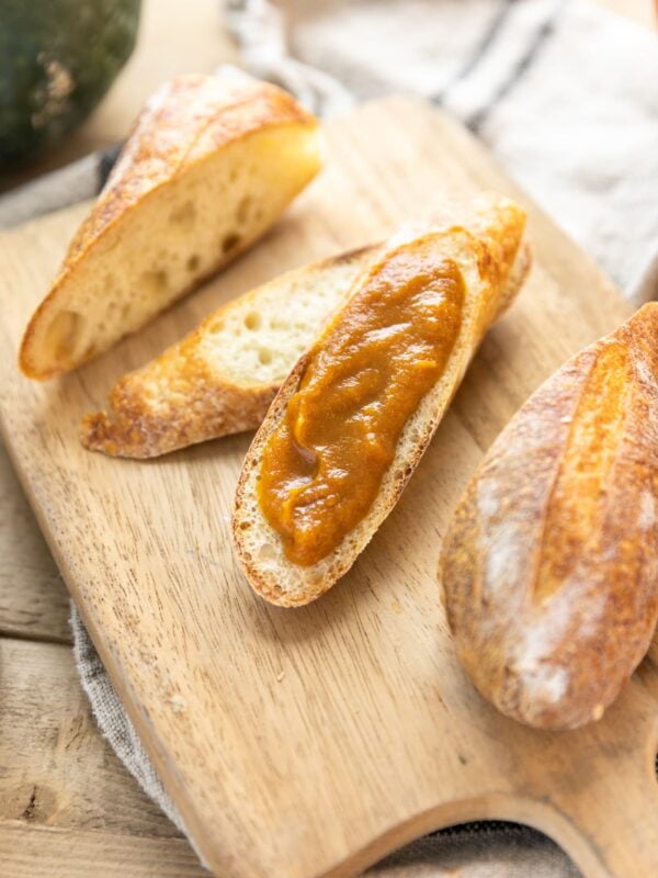 Top down view of pieces of French bread sliced apart and layered with brown colored pumpkin apple butter all on wood cutting board