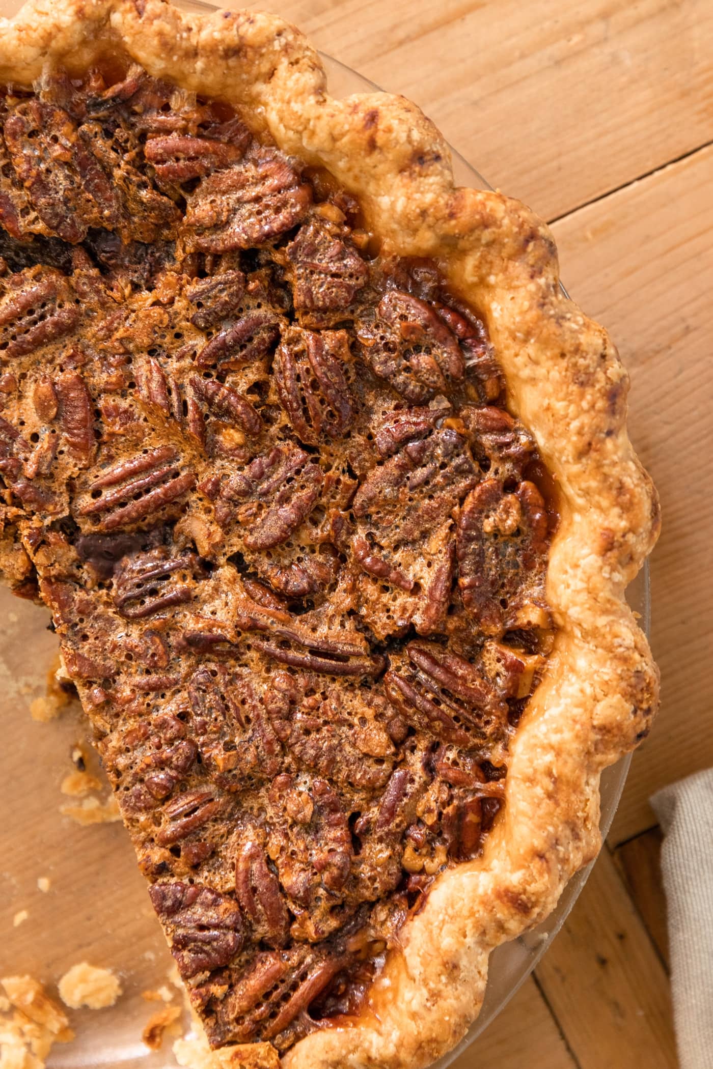Top down view of pecan pie sitting in pie dish with pecans all over the top sitting on wood surface