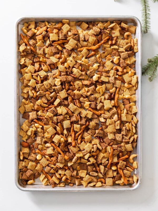 Top down view of baking sheet sitting on white surface filled with browned pieces of cereal after coming out of the oven